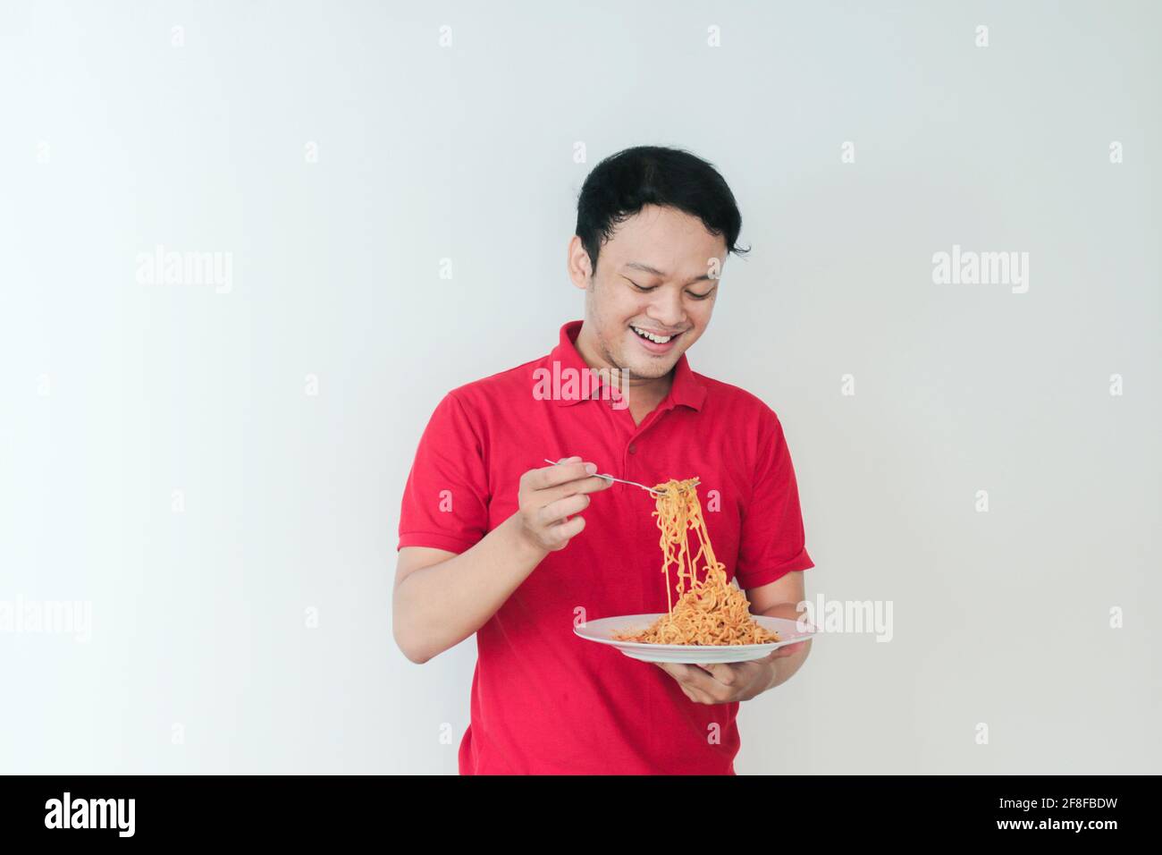 Portrait of happy Young Asian man enjoys noodles. Eating lunch concept. Stock Photo