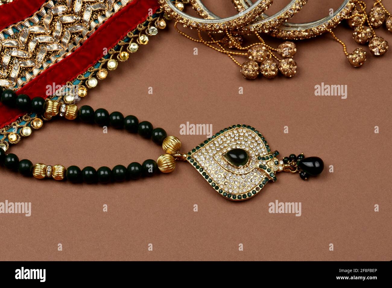Antique jewellery on a brown background, Golden scarf, Gold bracelet, Gold necklace, Gold earrings, finger ring indian traditional jewellery Stock Photo