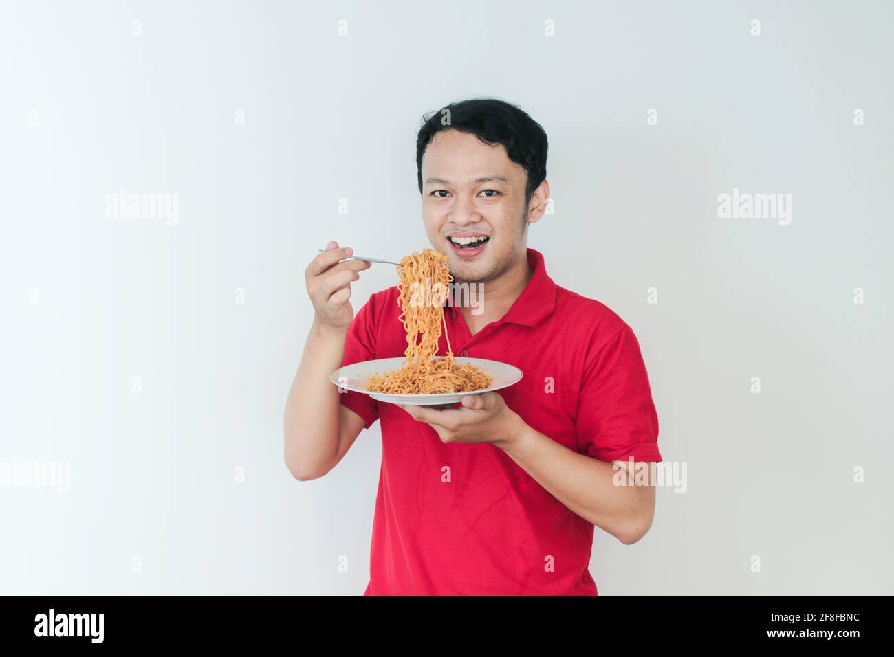 Portrait of happy Young Asian man enjoys noodles. Eating lunch concept. Stock Photo