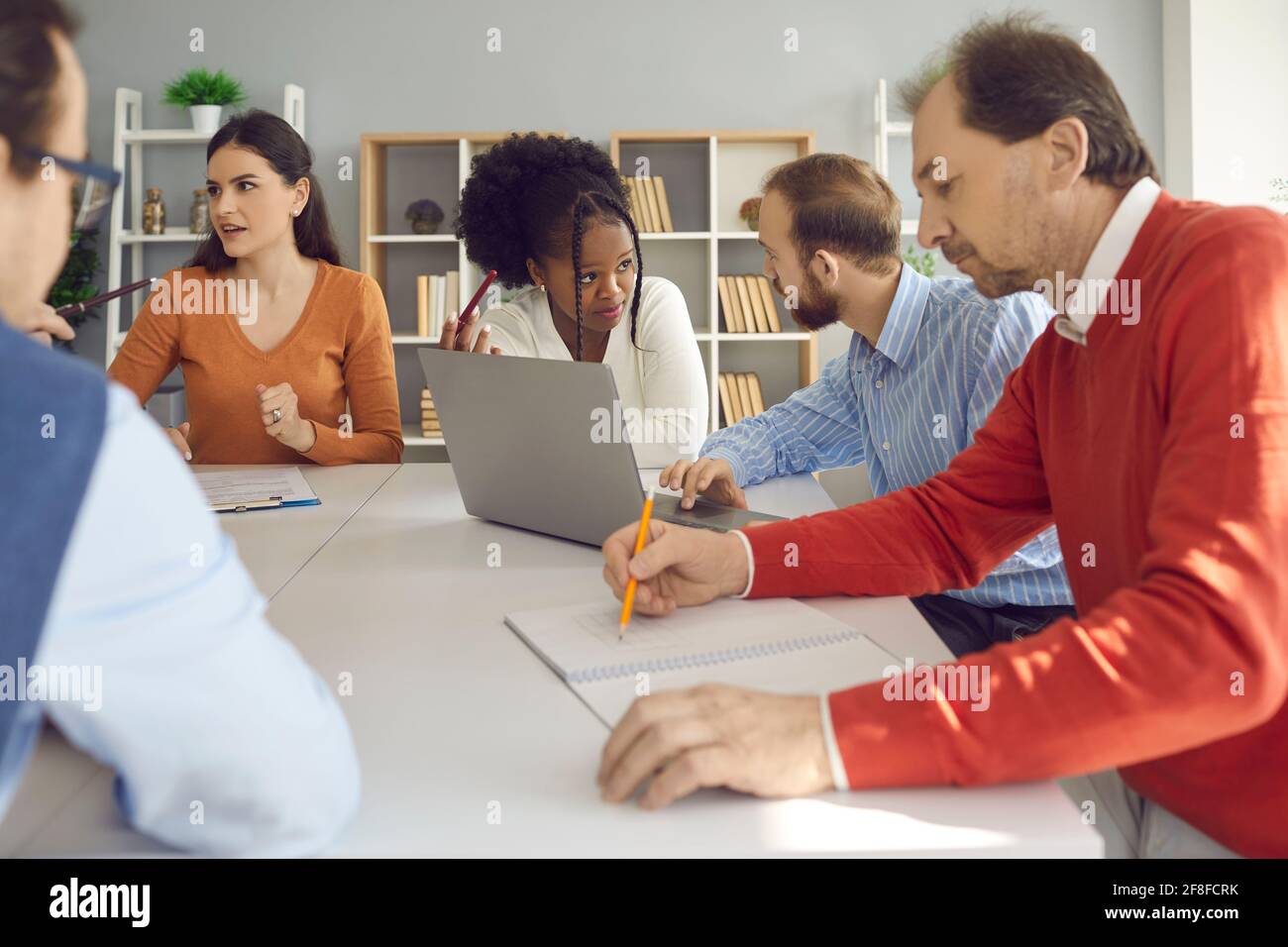 Group of diverse business people discussing their projects sitting at office table together Stock Photo