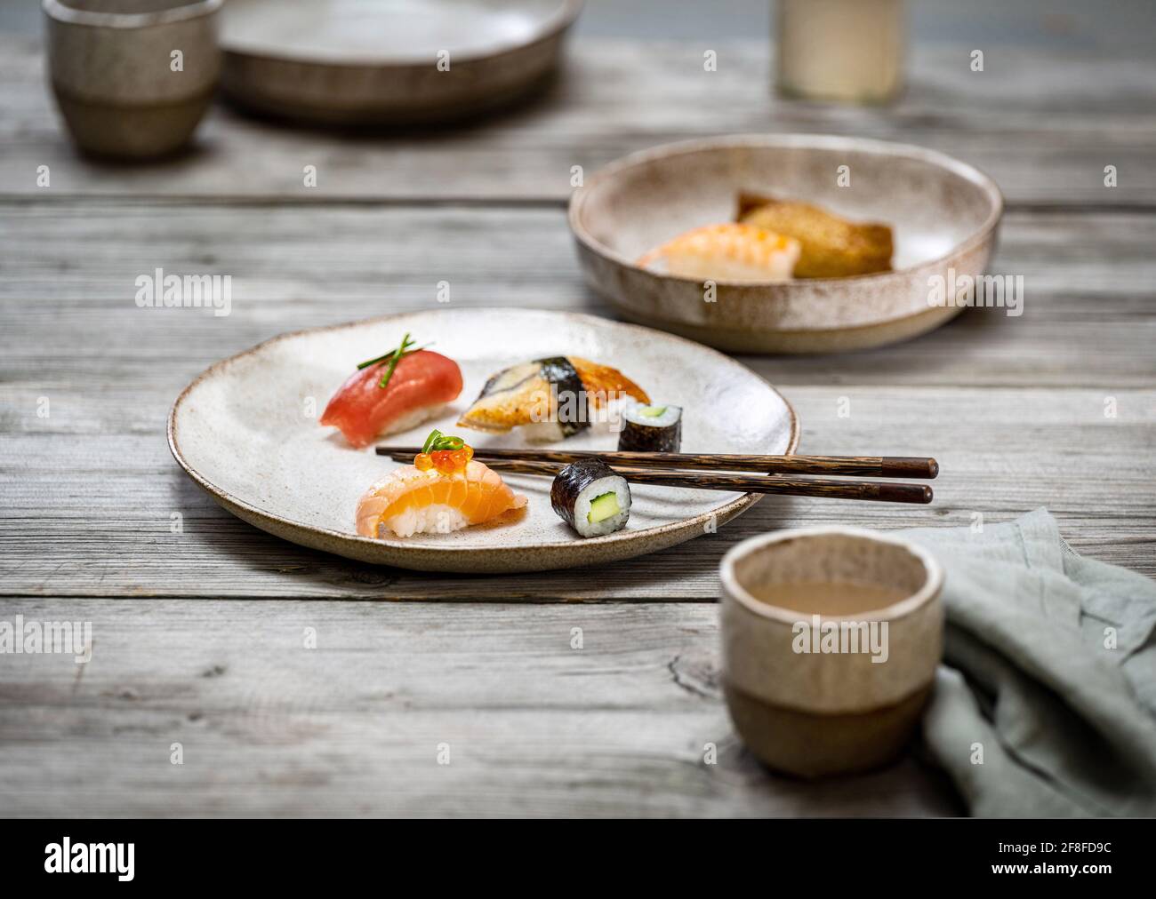 Food photo with sushi maki and nigiri on light ceramic plate arranged on a rough gray wooden table. Stock Photo