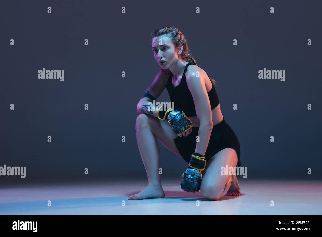 Portrait of young female MMA fighter isolated on blue background in neon Stock Photo