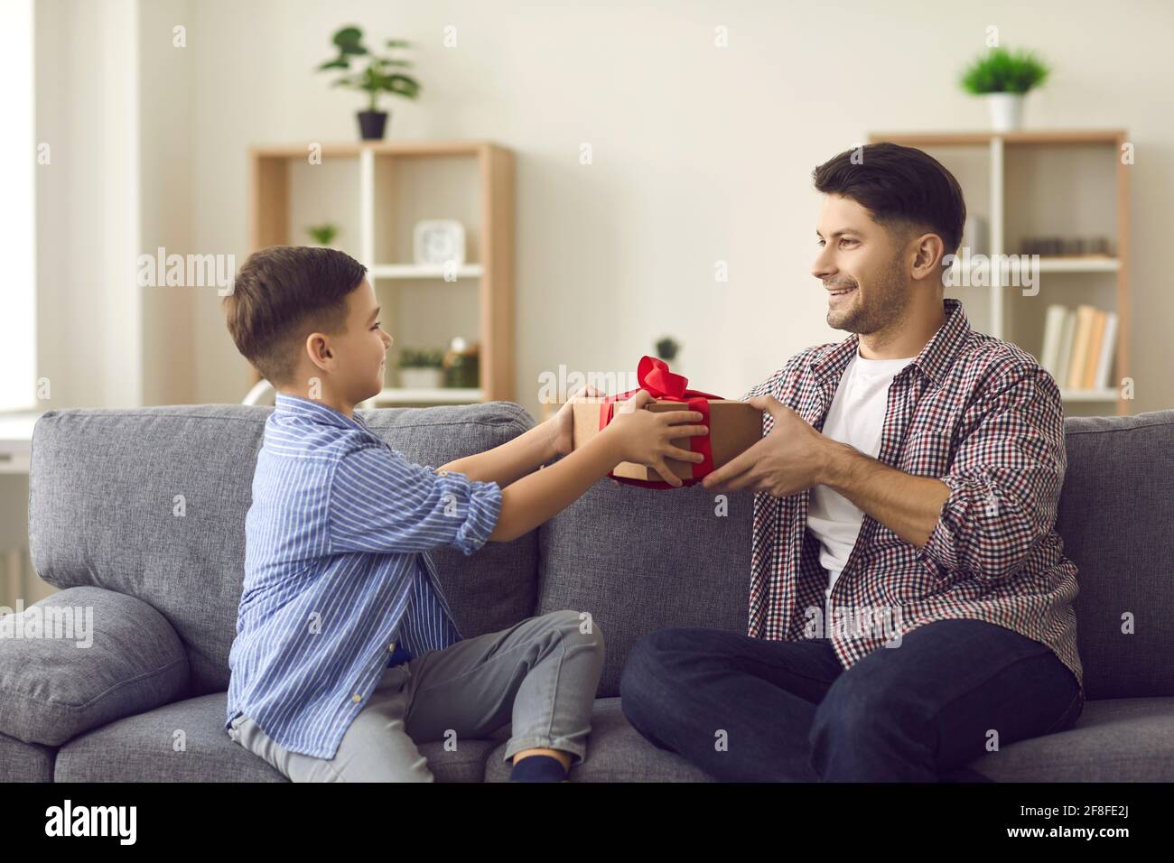 Cute boy gives congratulations to his dad on the holiday and gives him a gift box. Stock Photo
