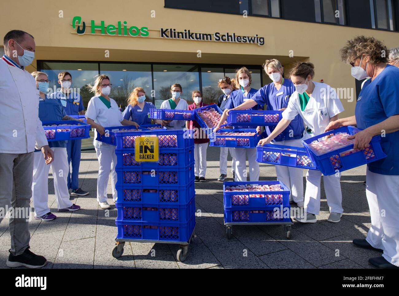 Schleswig, Germany. 14th Apr, 2021. Klaus-Dieter Lemmermann (l), master baker, hands over a delivery of quark balls to nurses at Helios Klinikum Schleswig. Under the motto 'Something sweet for the soul', numerous bakers in the north pay tribute to the efforts of doctors, nurses, educators, police officers, firefighters and other helpers during the Corona pandemic. Credit: Christian Charisius/dpa/Alamy Live News Stock Photo