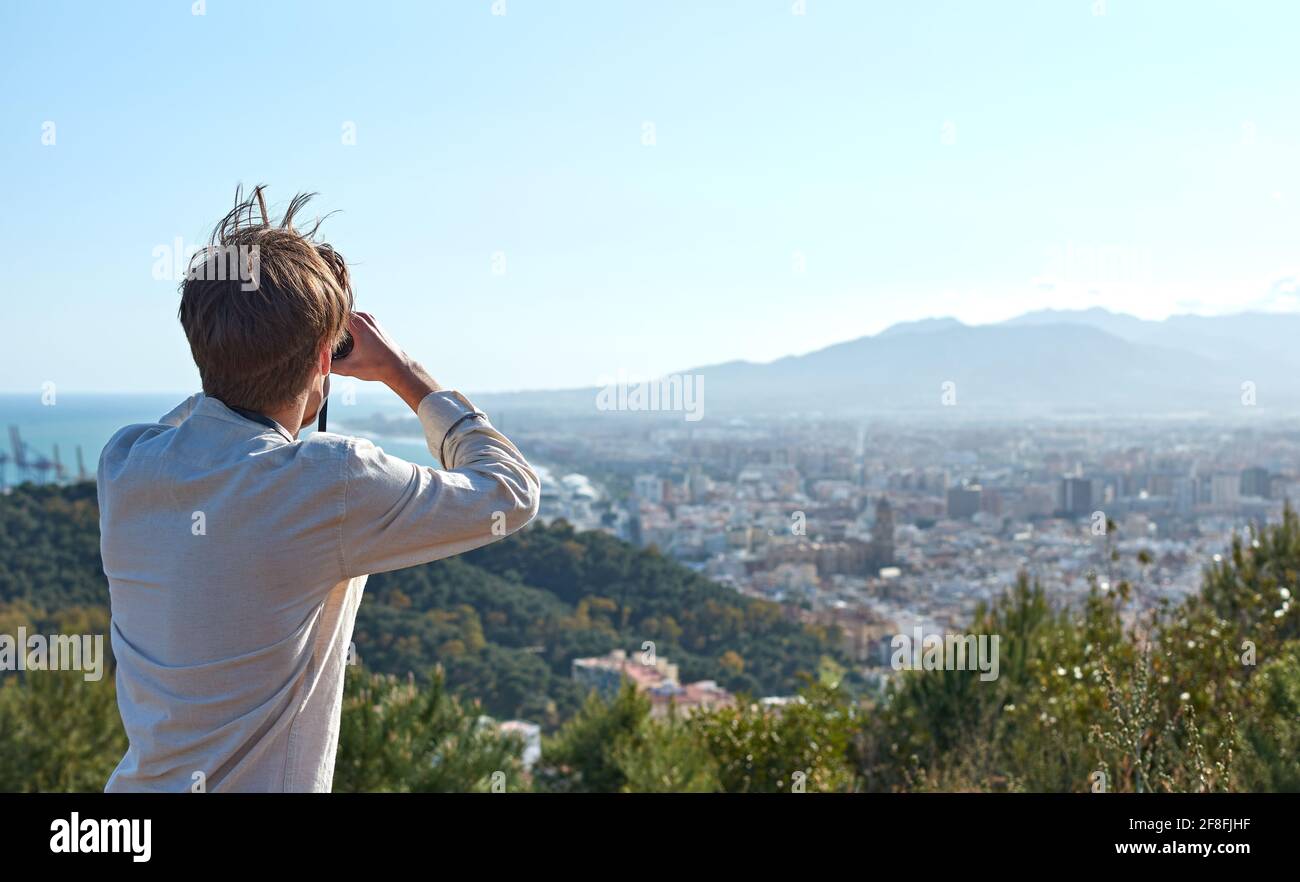 Spanish adventurous male traveler using binoculars and admiring the