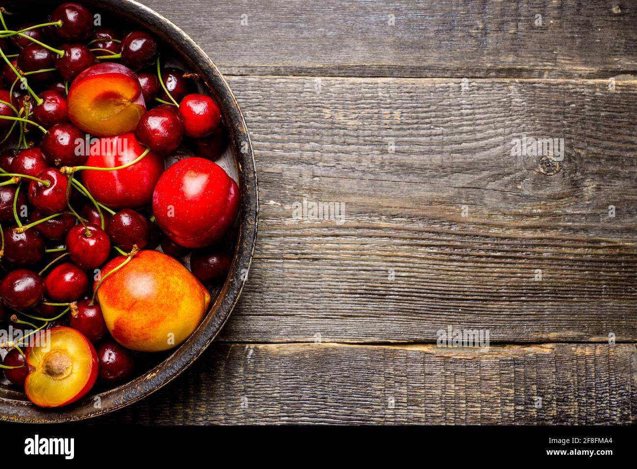 Ripe plums, nectarines and cherries in rustic pan. Selective focus. Stock Photo