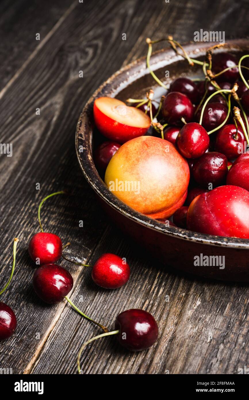 Ripe plums, nectarines and cherries in rustic pan. Selective focus. Stock Photo