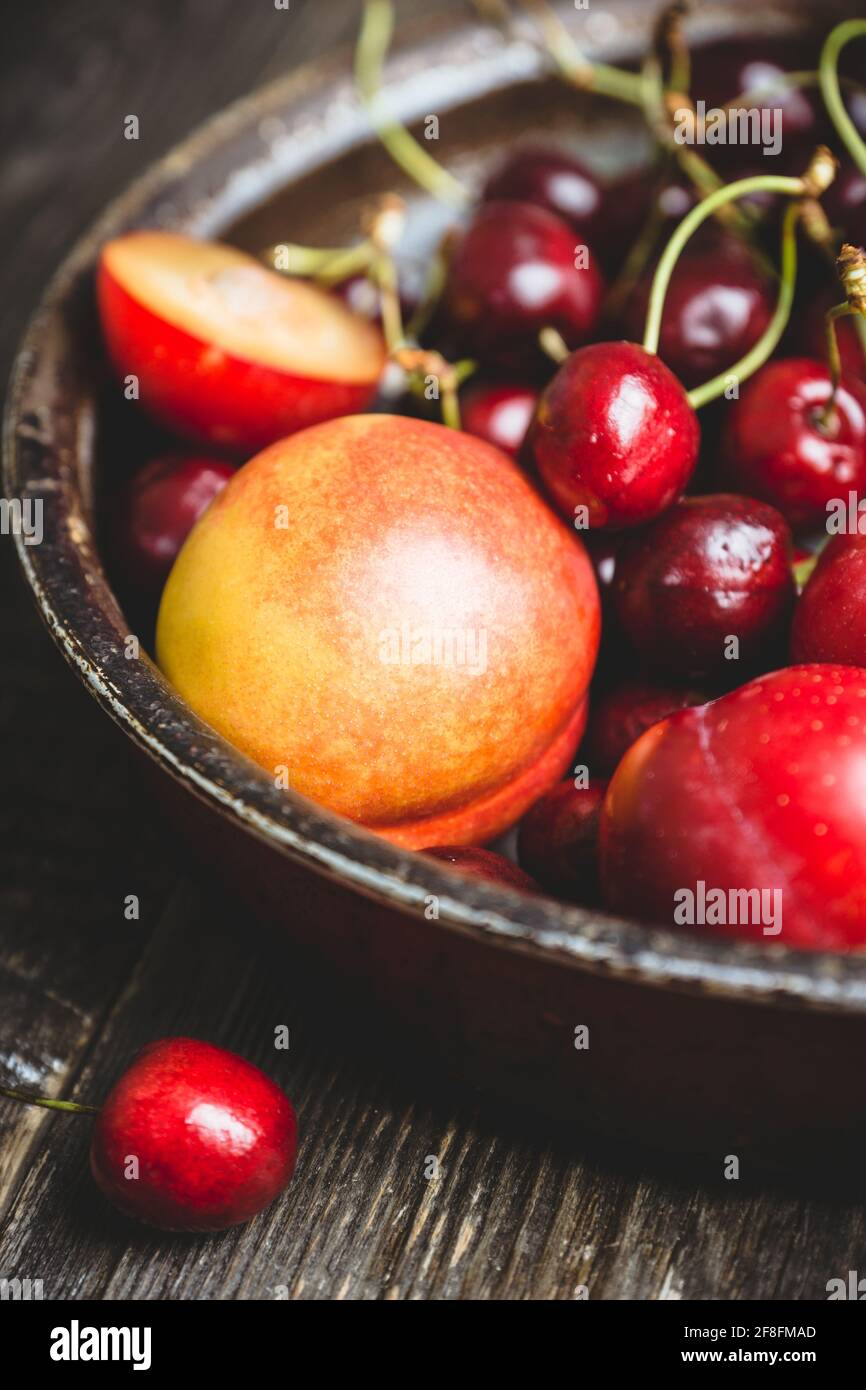 Ripe plums, nectarines and cherries in rustic pan. Selective focus. Stock Photo