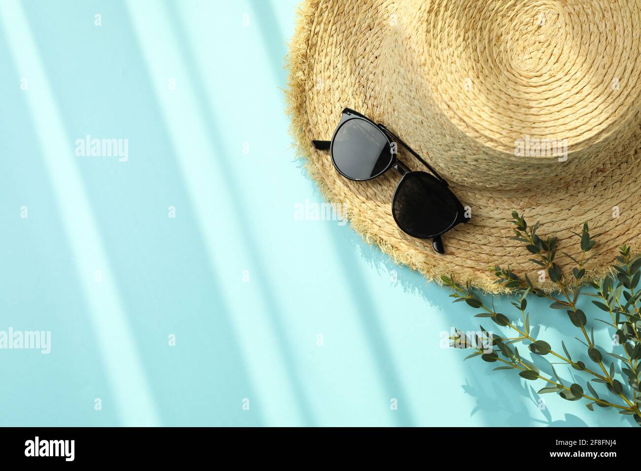 Straw hat, branch and sunglasses on blue background Stock Photo - Alamy