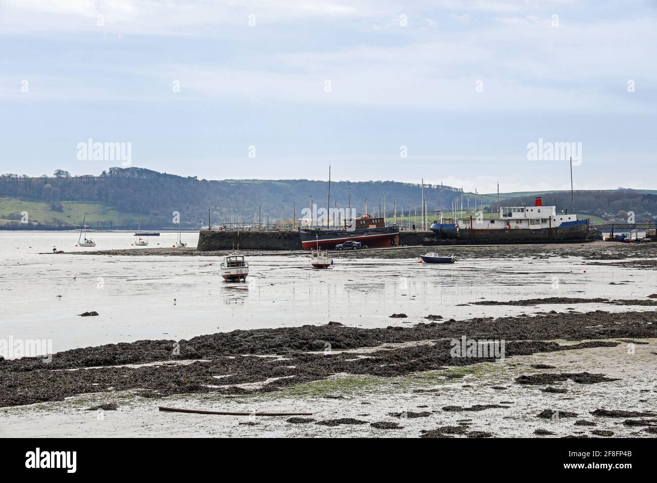 The riverside at Torpoint in south east Cornwall, with boats berthed on the harbour wall. In the distance Mount Edgcumbe. Stock Photo