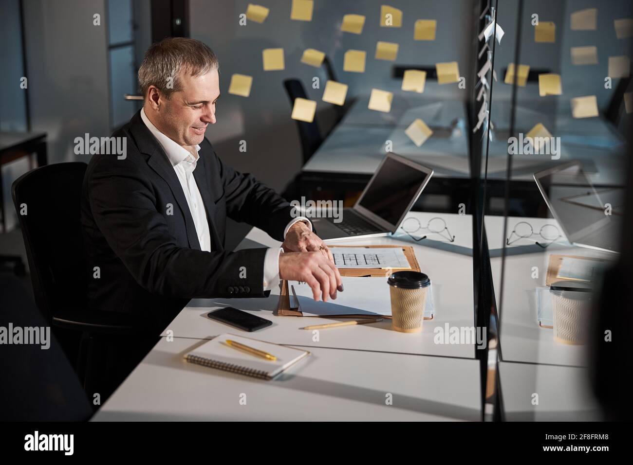 Cheerful businessman is doing paperwork in office Stock Photo