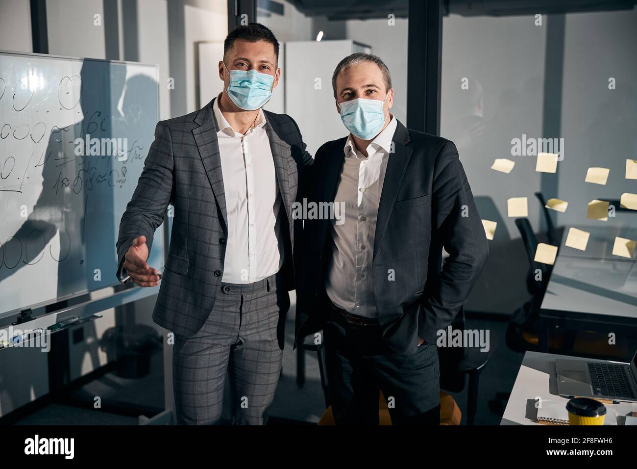 Business colleagues in medical masks standing in office Stock Photo - Alamy