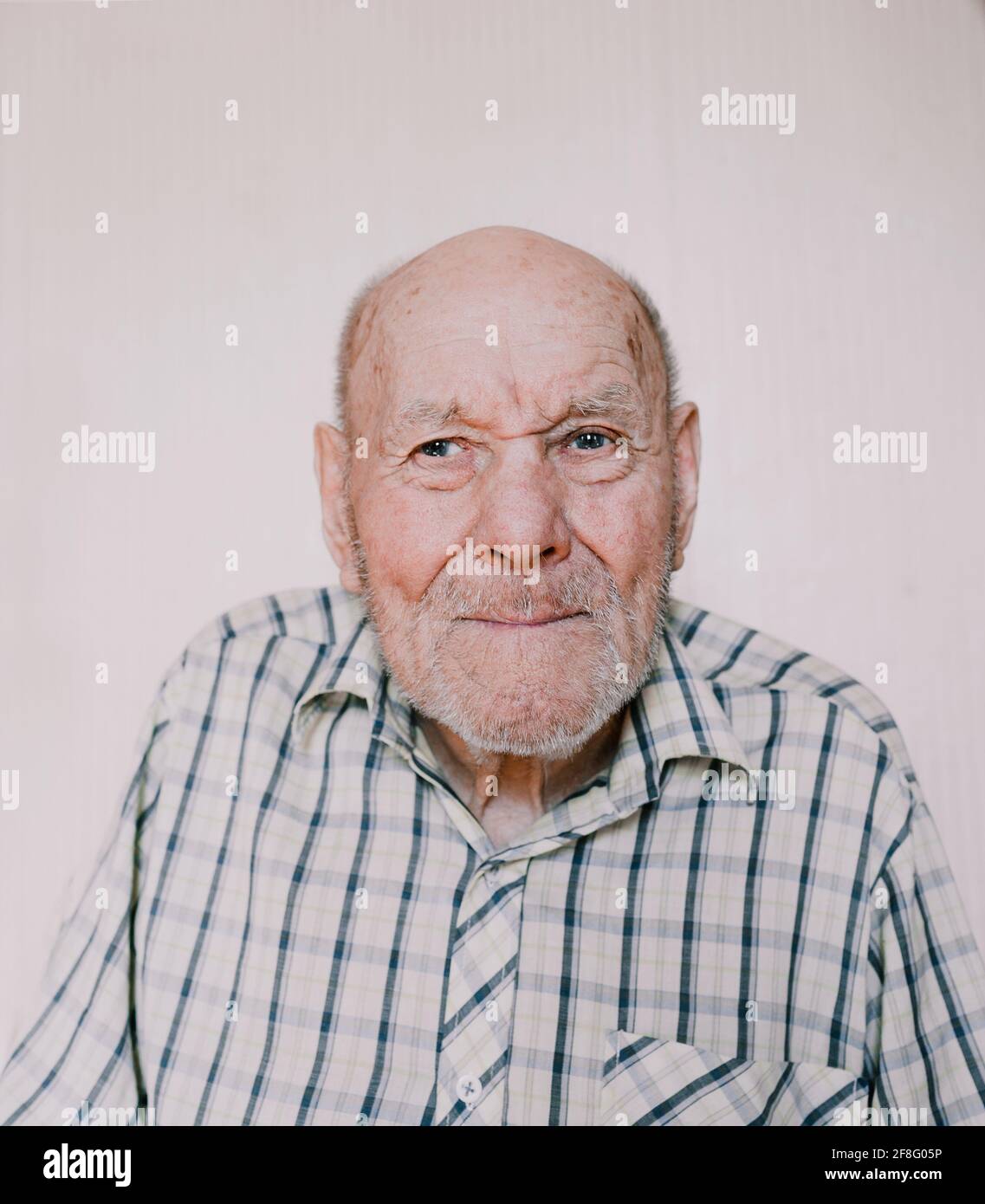 a large portrait of an old man on a light background with deep wrinkles, age spots. Stock Photo