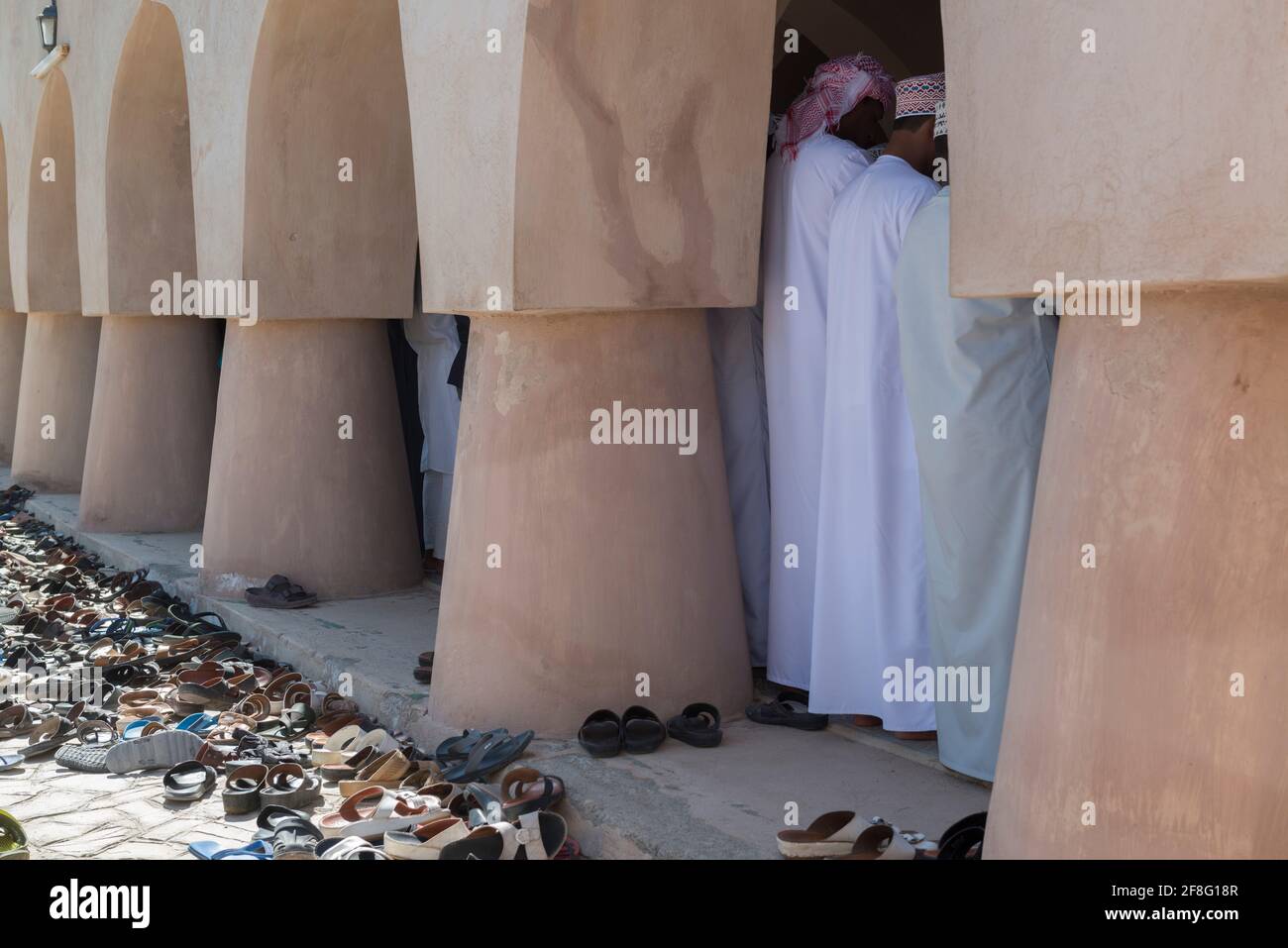 Lots of shoes next to the prayer hall of the Jami Al Hamoda mosque in the town Jalan Bani Ben Ali. Ash Sharqiyah South Governorate. Oman Stock Photo