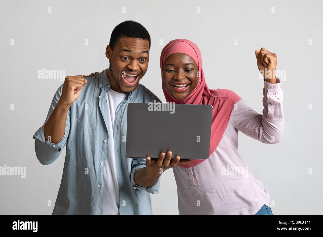 Joyful black couple celebrating win with laptop Stock Photo - Alamy