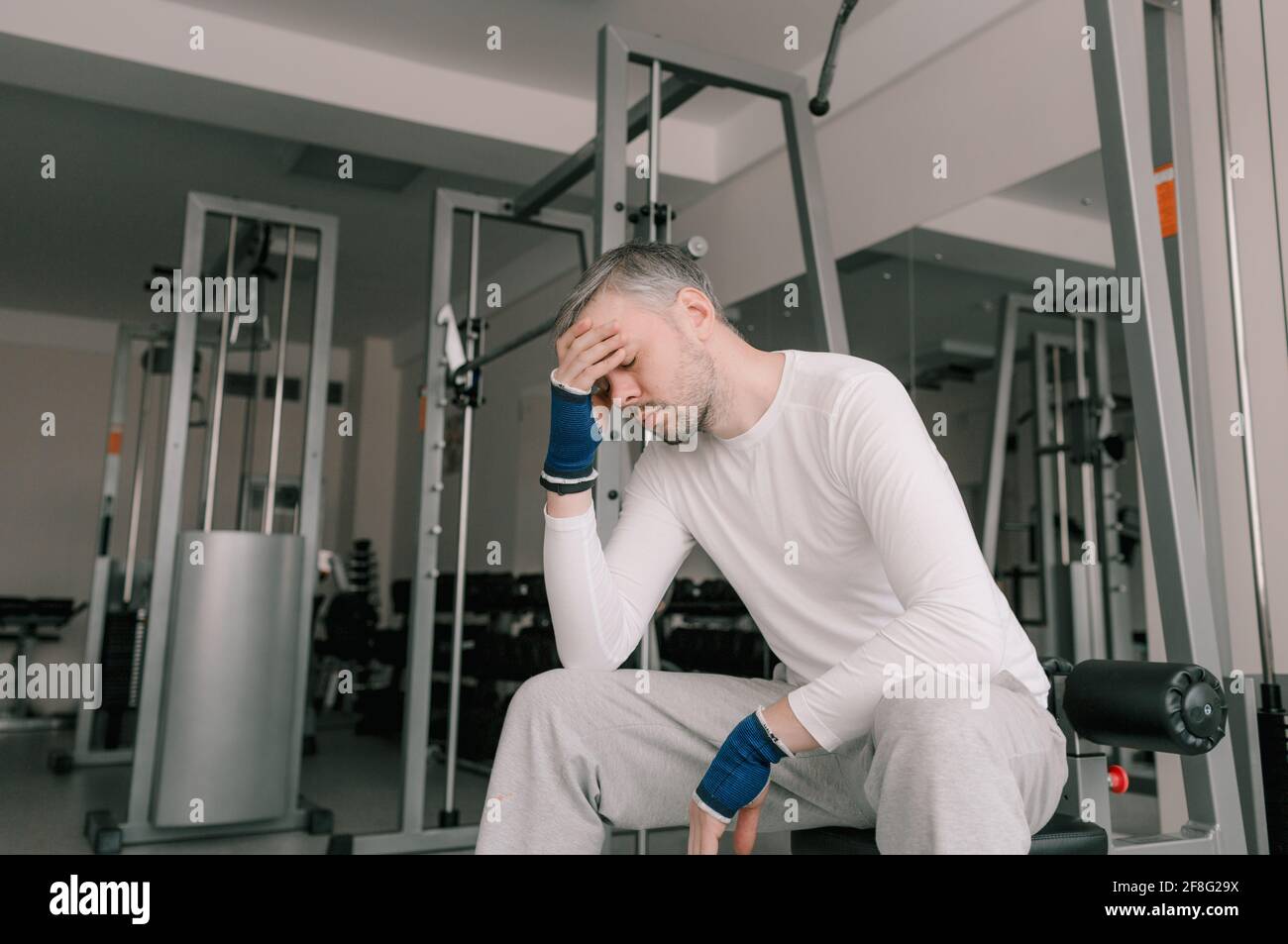 a tired athlete after a hard workout sits and rests with his hand