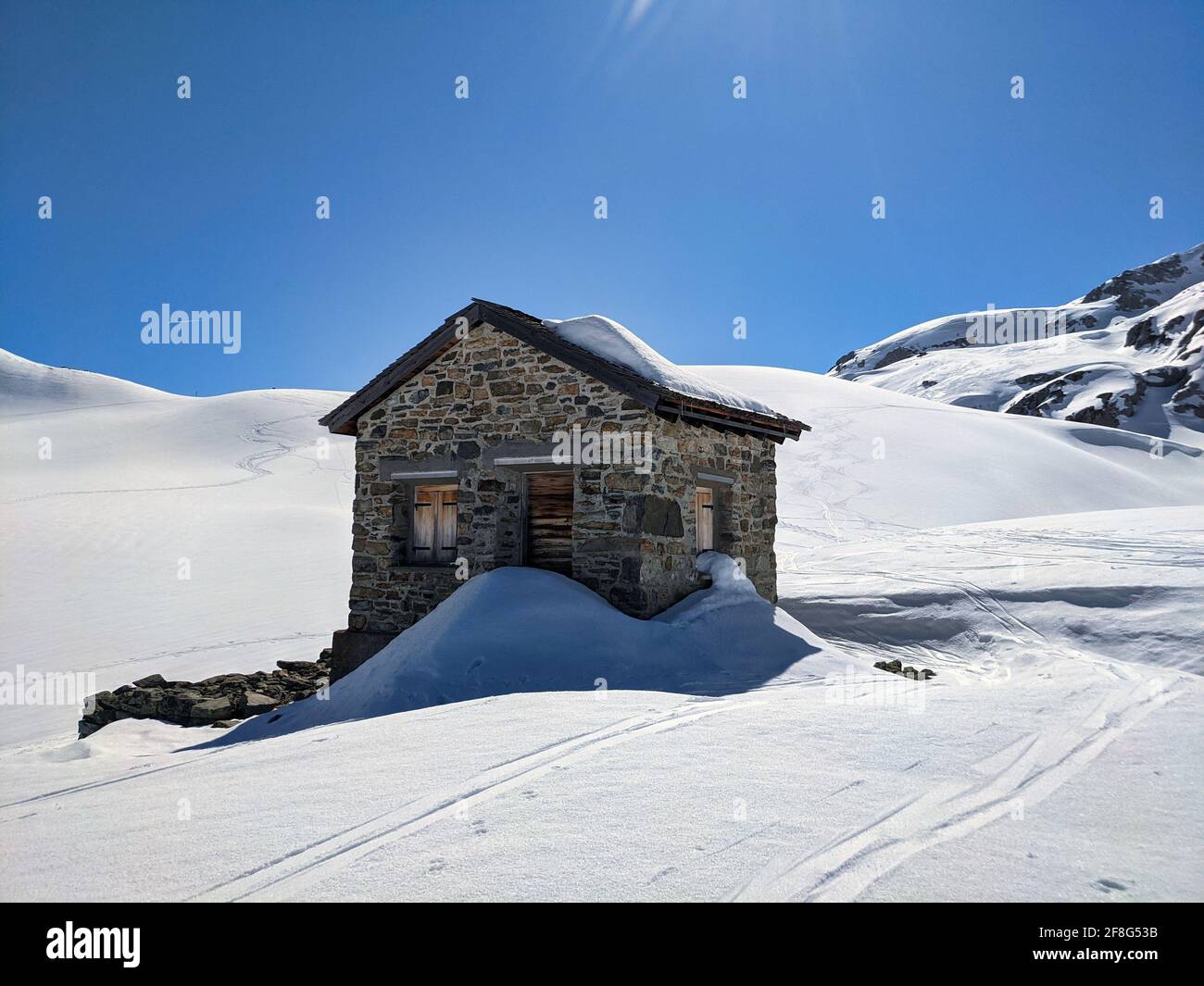 old customs hut between the austrian and swiss border on the plasseggenpass. Sunny ski tour in the mountains. blue sky Stock Photo