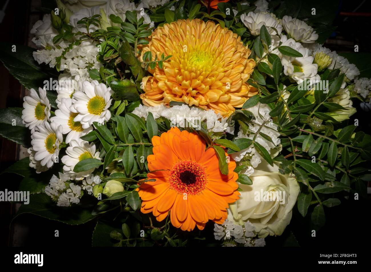 A closeup picture of a bouquet of funeral flowers. White, yellow and