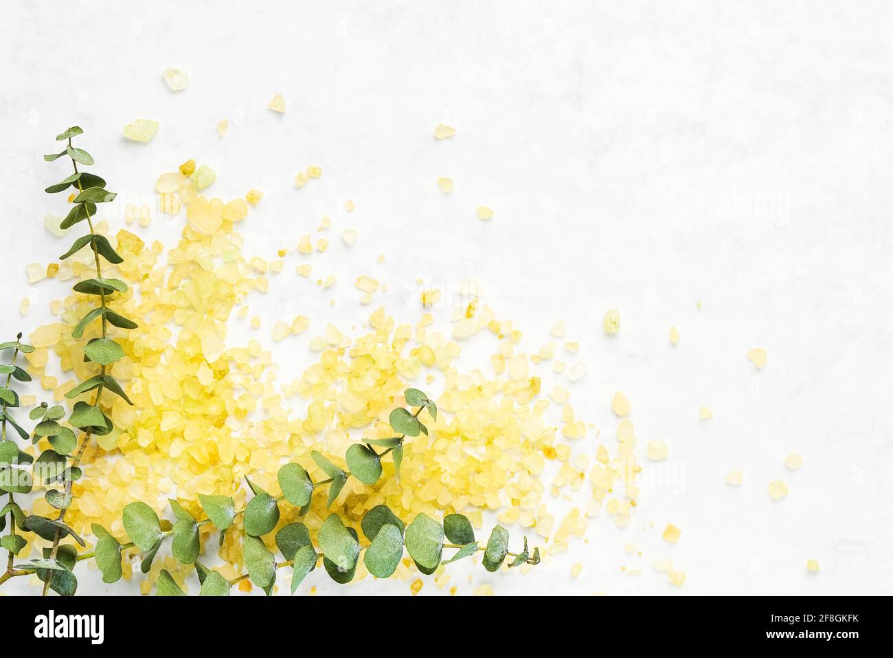Yellow bath salt and eucalyptus branch on white background. SPA concept. Copy space for text, flat lay Stock Photo