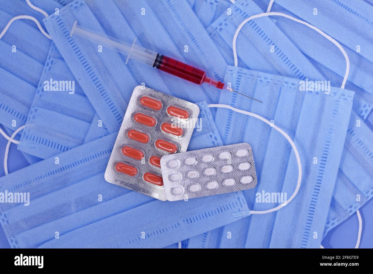 Protective medical mask, pills , syringe on blue background, corona virus protection, coronavirus, covid19 Global pandemic Stock Photo