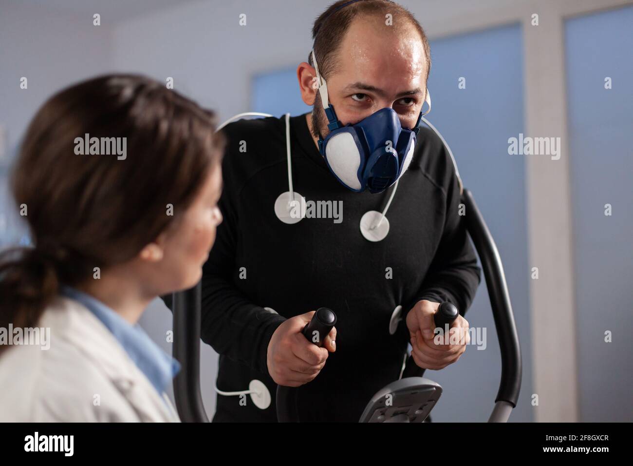 Fitness researcher monitoring performance athlete with sensors attached