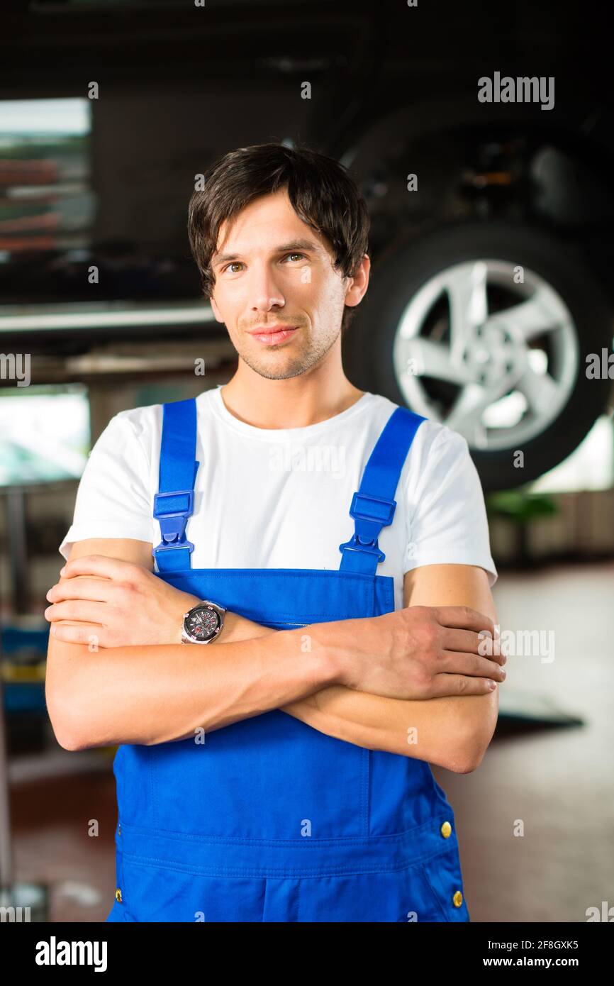 Auto mechanic standing in his in front of a car on a hoist