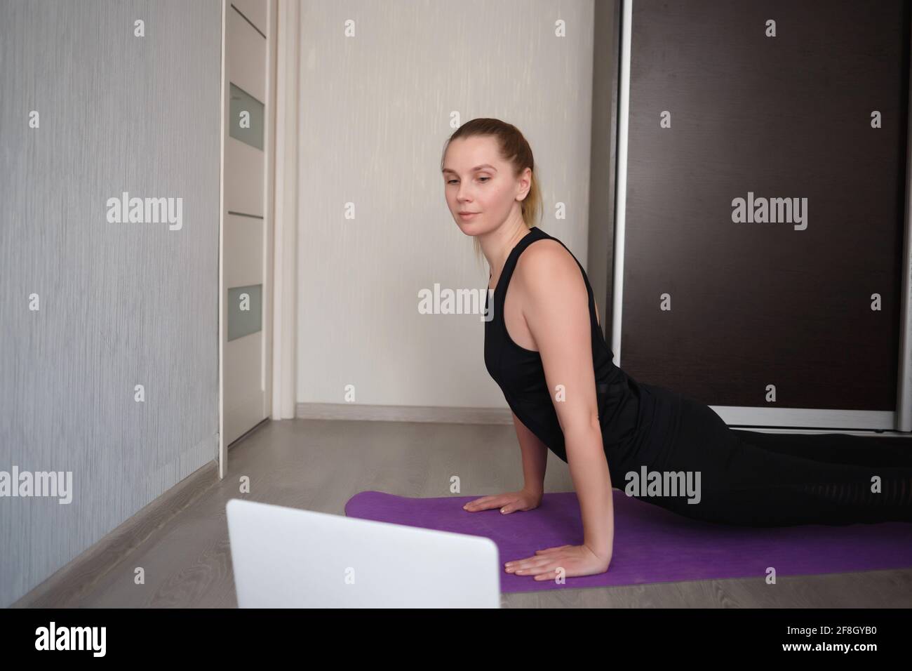 young woman doing asana at home on yoga mat in front of laptop Stock ...