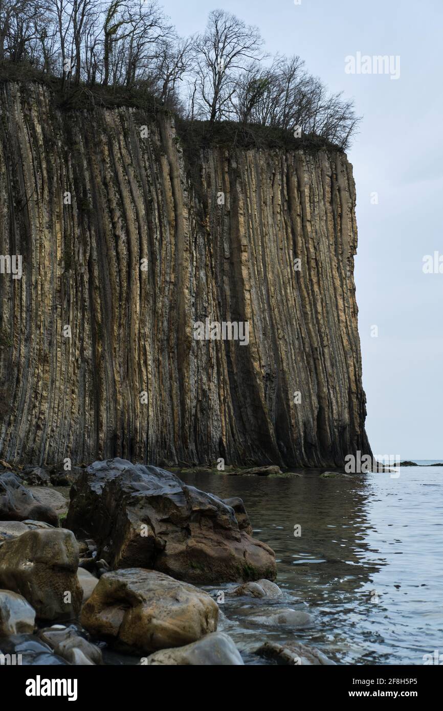 Rocks and blue sea. Side view of a huge mountain facing the ocean ...