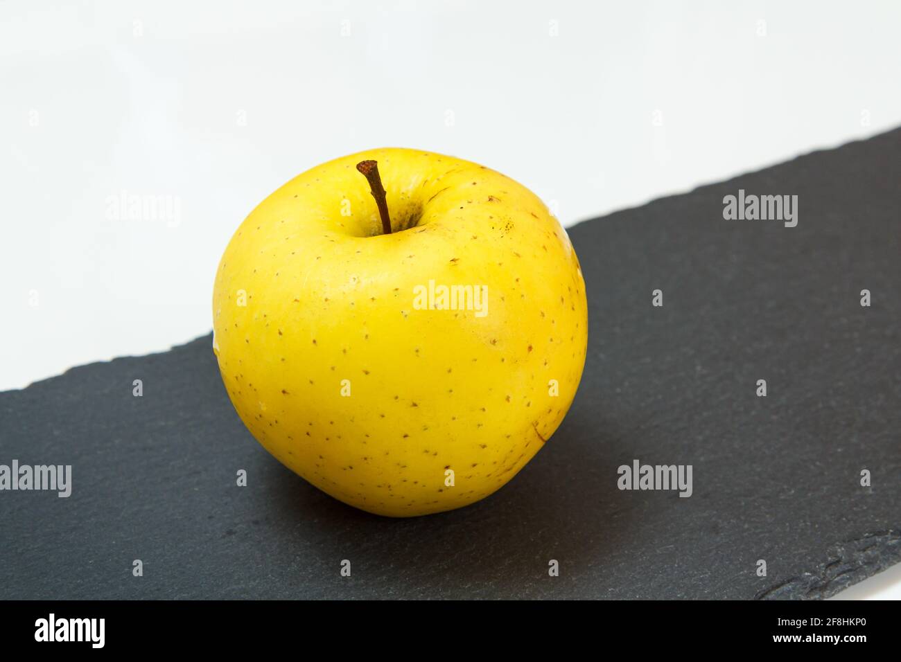 Yellow apple fruit on the black stone board and white background — free download
