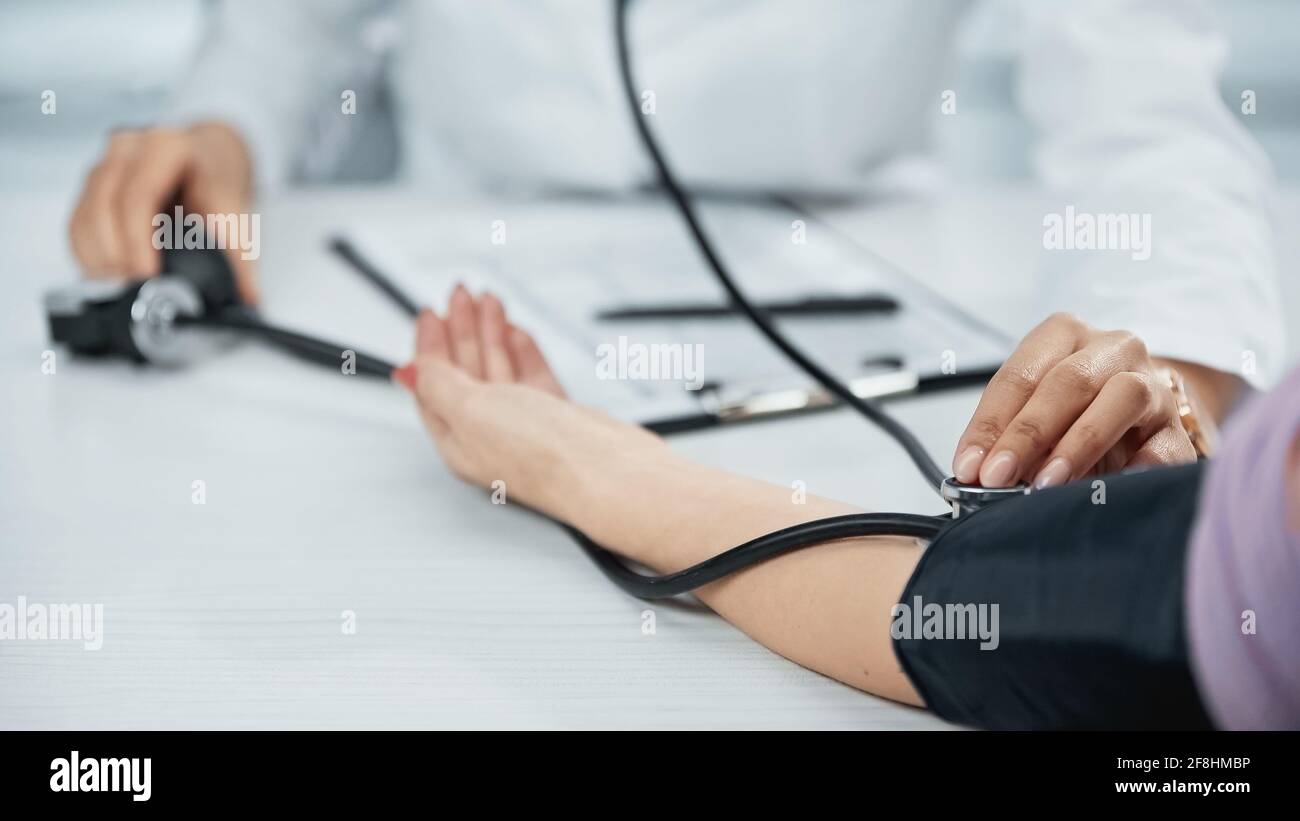 partial view of african american doctor in white coat measuring blood