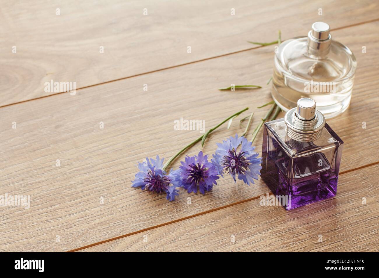 Bottles of perfumes with knapweeds flowers on wooden boards. Top view. Stock Photo