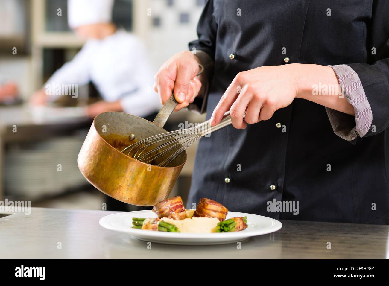 Chef in hotel or restaurant kitchen cooking, only hands to be seen, he