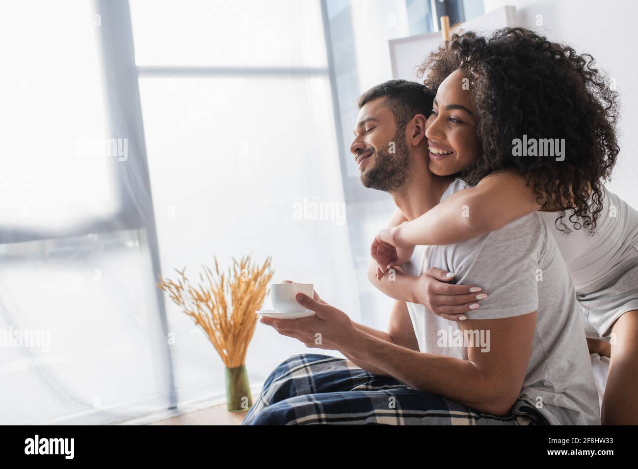 happy african american woman hugging bearded boyfriend with cup of ...