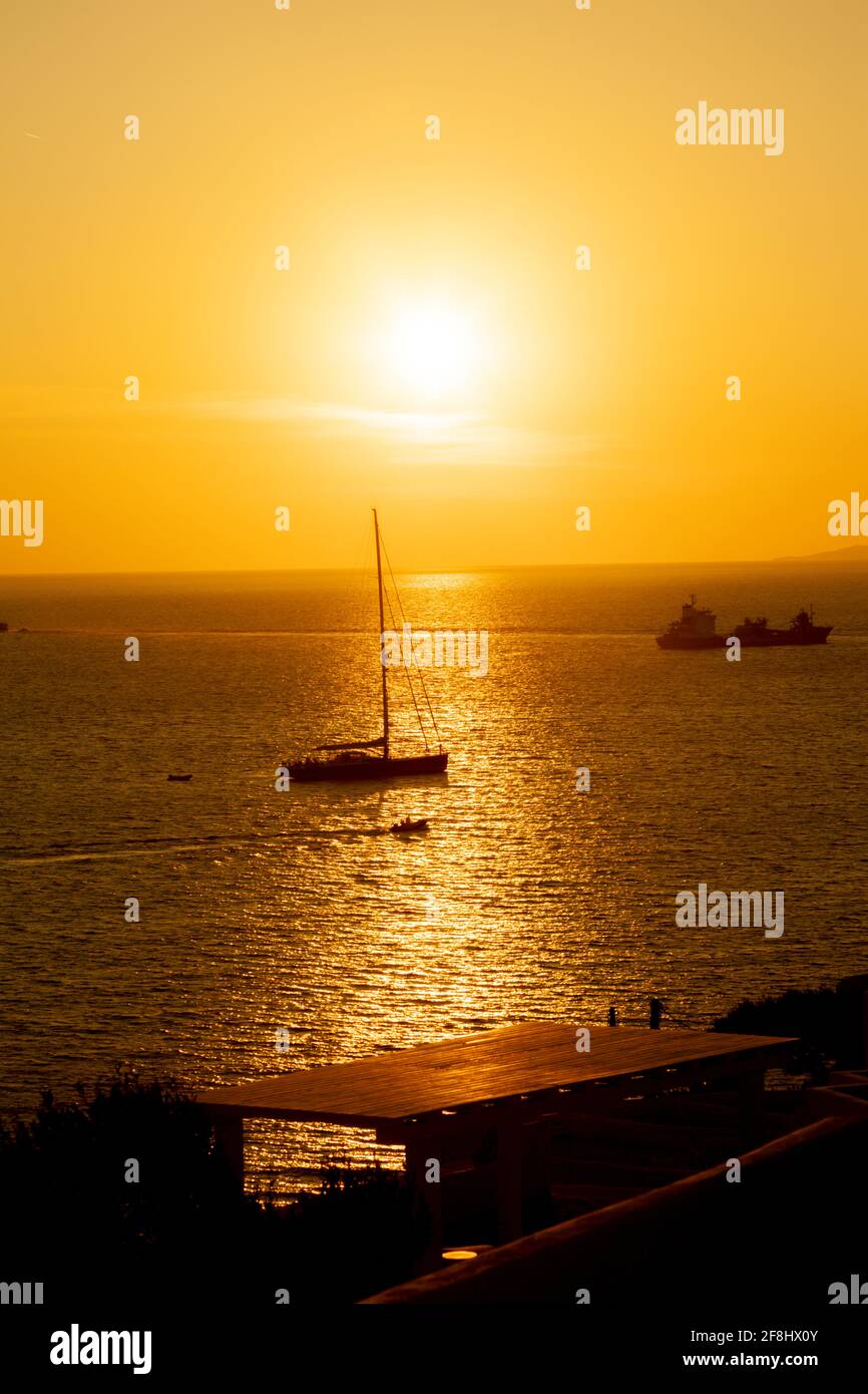 Romantic sunset with sailing boat in Mykonos island, a popular vacation resort of the Cyclades islands, Aegean Sea, Greece, Europe Stock Photo