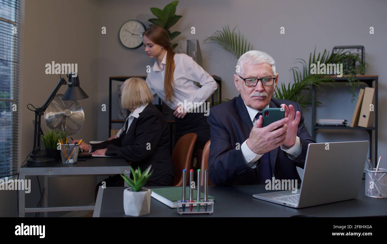 Senior businessman grandfather with mobile phone texing message working watching video communicating Stock Photo