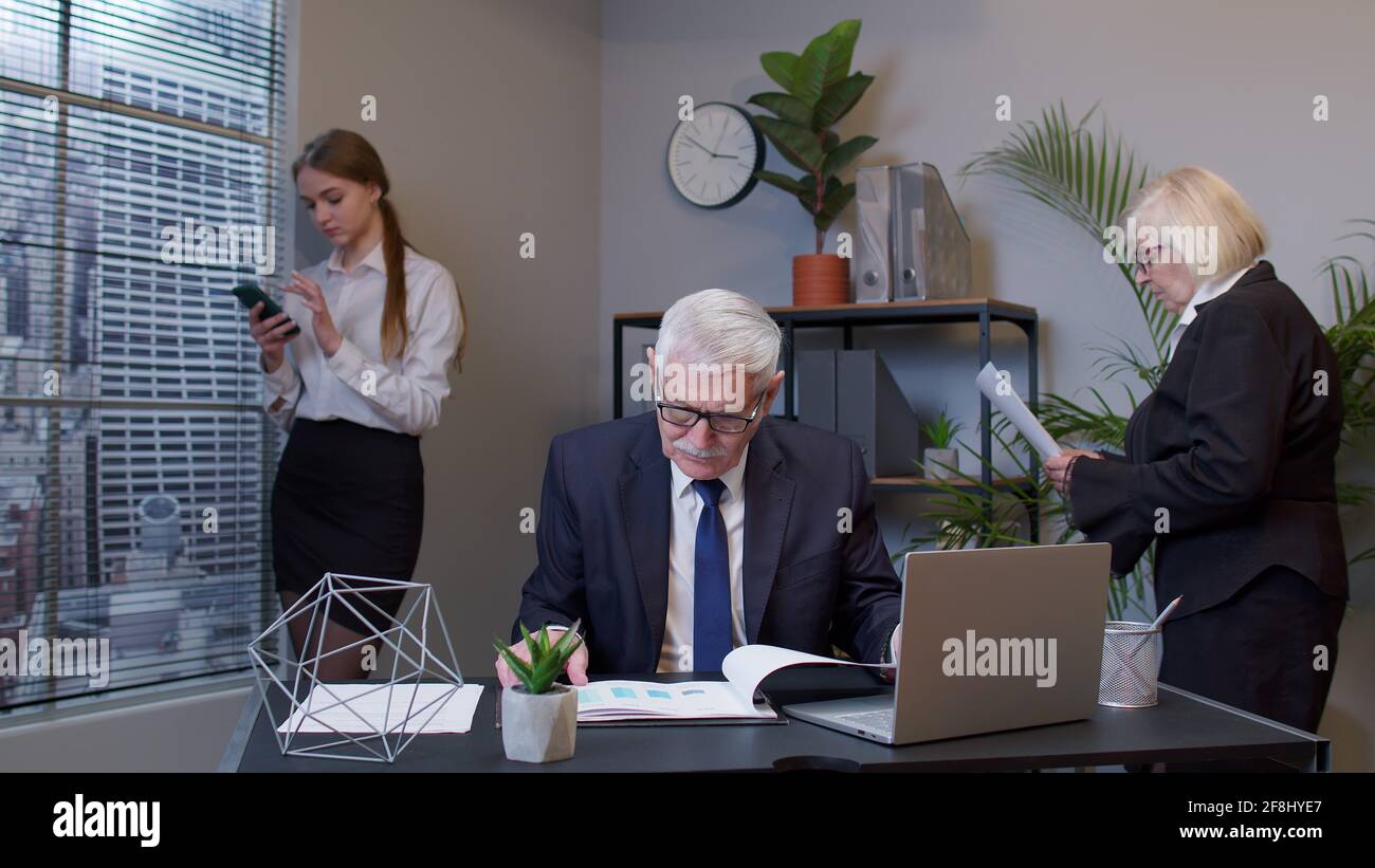 Senior freelancer concentrated developing project while working, typing on laptop computer in office Stock Photo