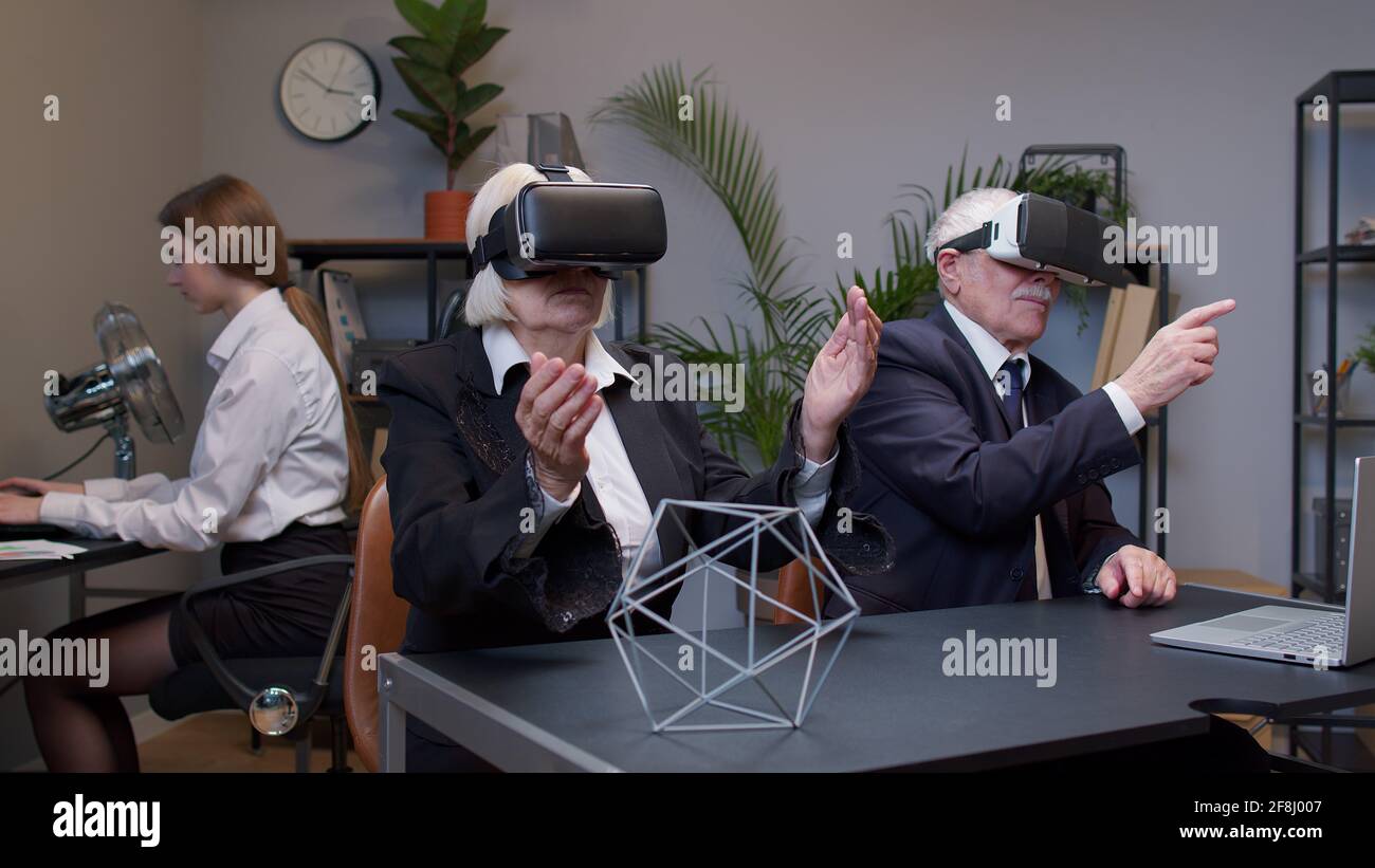 Senior business colleagues using virtual reality 3D app headset helmet ...