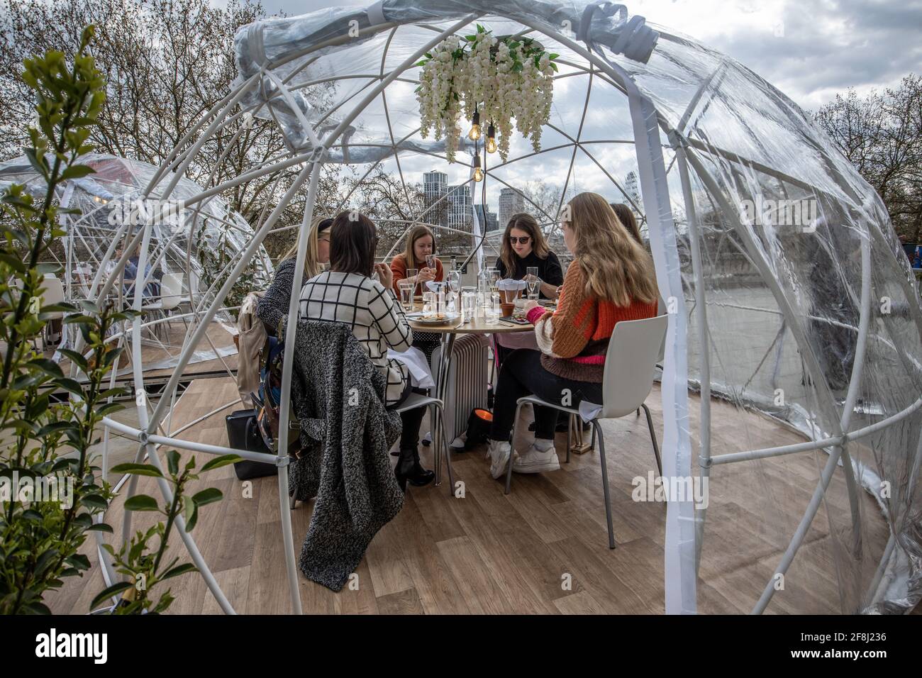 Friends enjoy one of Somerset House’s igloo-style dining domes where groups of up to six can eat and drink while looking out at the Thames, London, UK Stock Photo