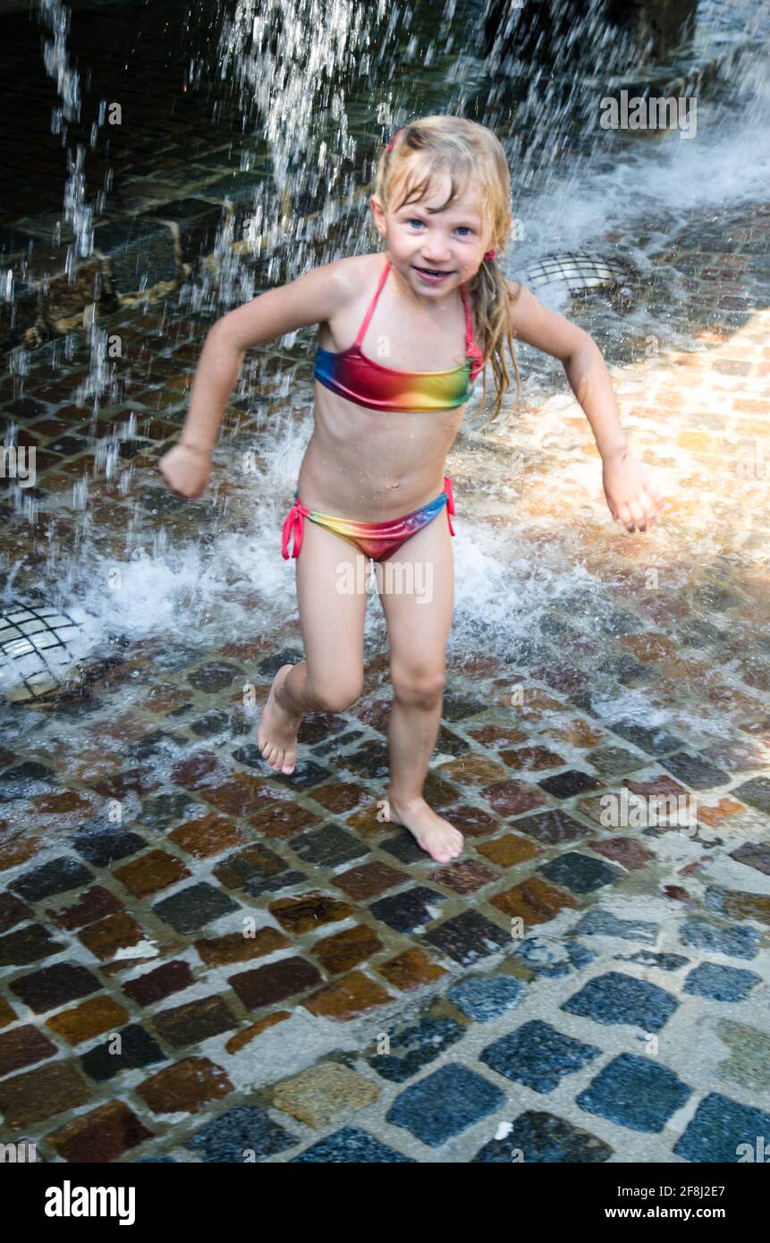 little blond girl playing with water falling down Stock Photo