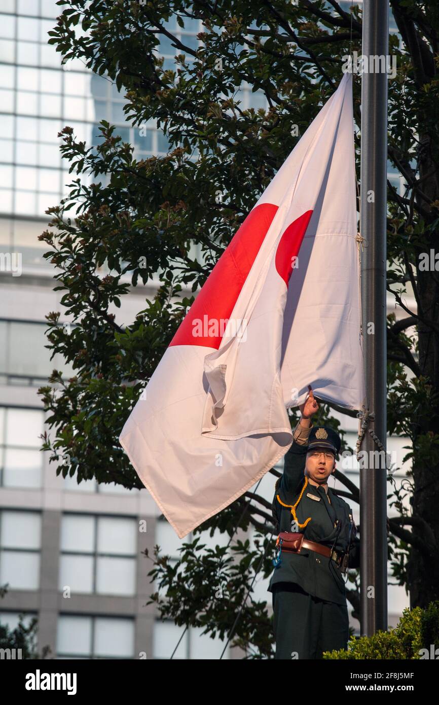 Japanese uniformed guard raising/lowering Japanese flag, Shinjuku, Tokyo, Japan Stock Photo
