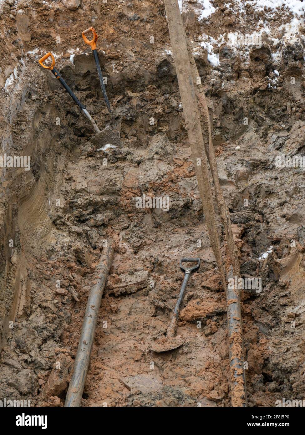 a hole dug in the clay soil for laying underground utilities. Work on