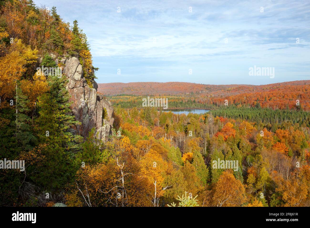 Cliff and small lake surrounded by trees in autumn color in northern Minnesota Stock Photo