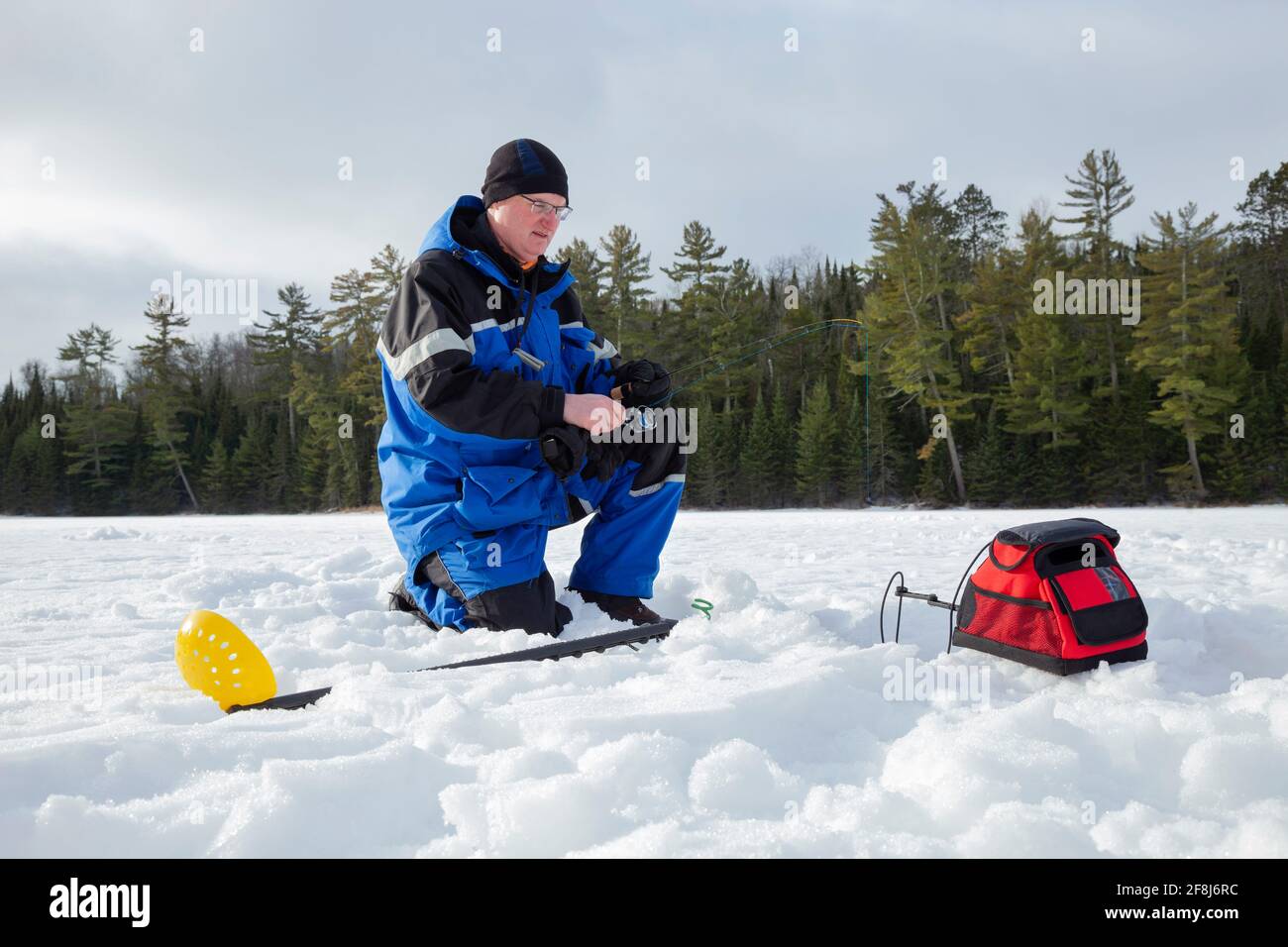 Man ice fishing on a northern Minnesota lake on a winter morning Stock Photo