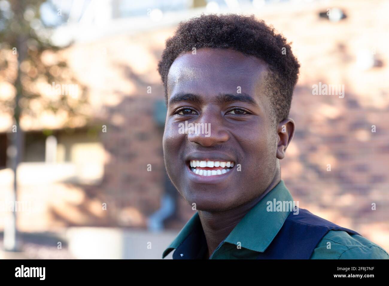 A handsome smiling young black student stands in front of his college Stock Photo