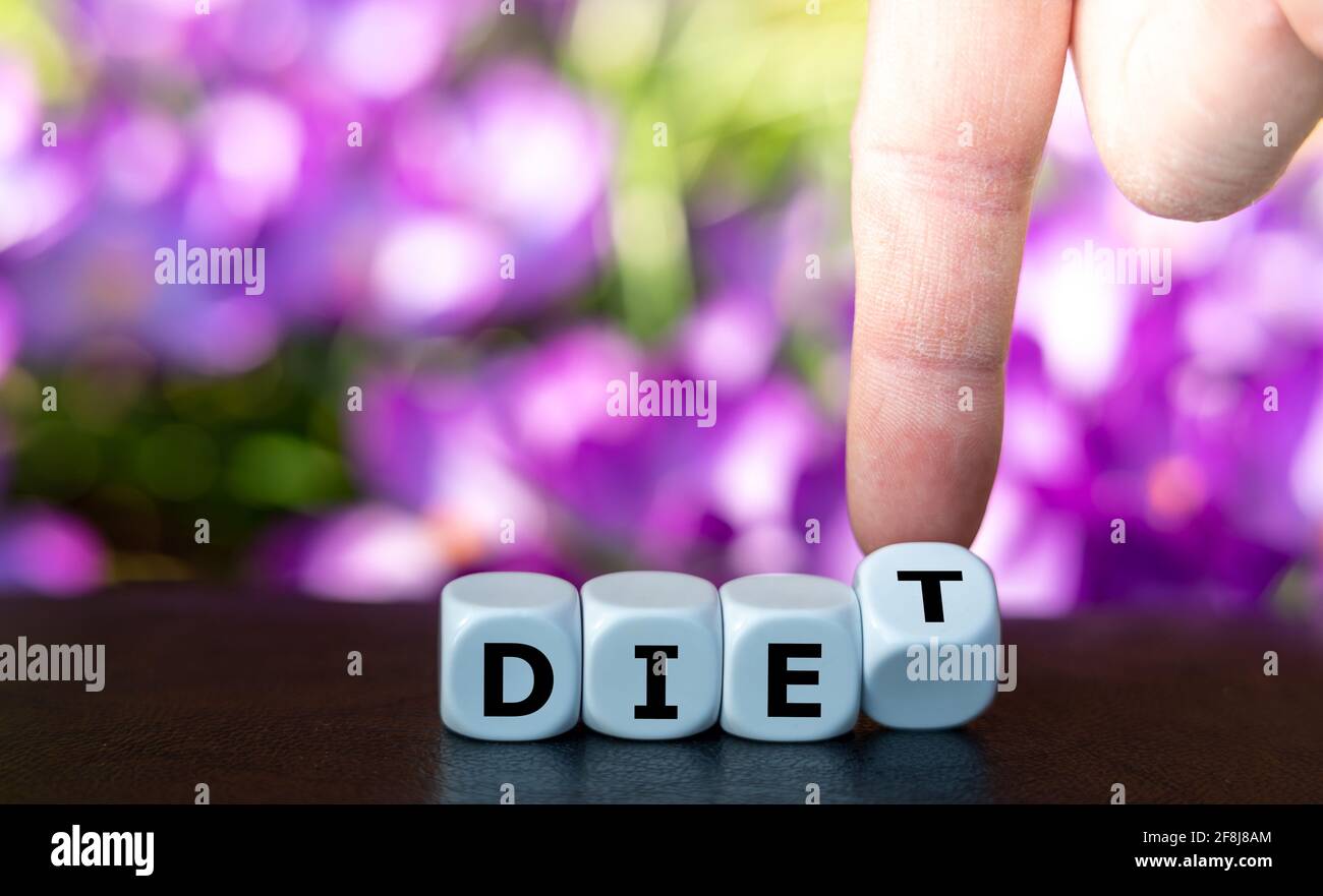 Symbol to start a diet. Hand turns dice and changes the word 'die' to 'diet'. Stock Photo