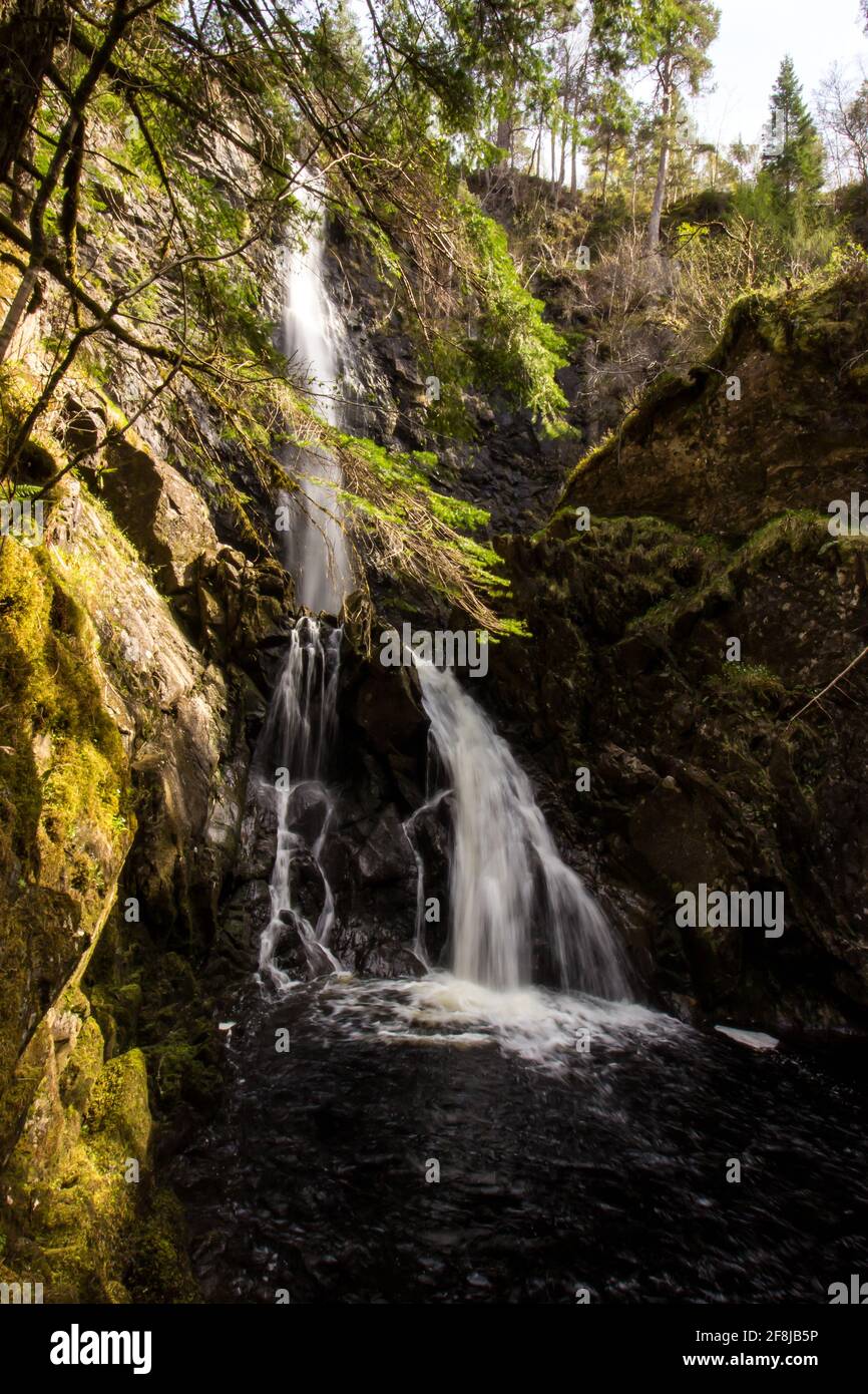 View of the base of the plodda falls, a waterfall in glen Affric Scotland, on a sunny day cascading down into a moss covered ravine Stock Photo
