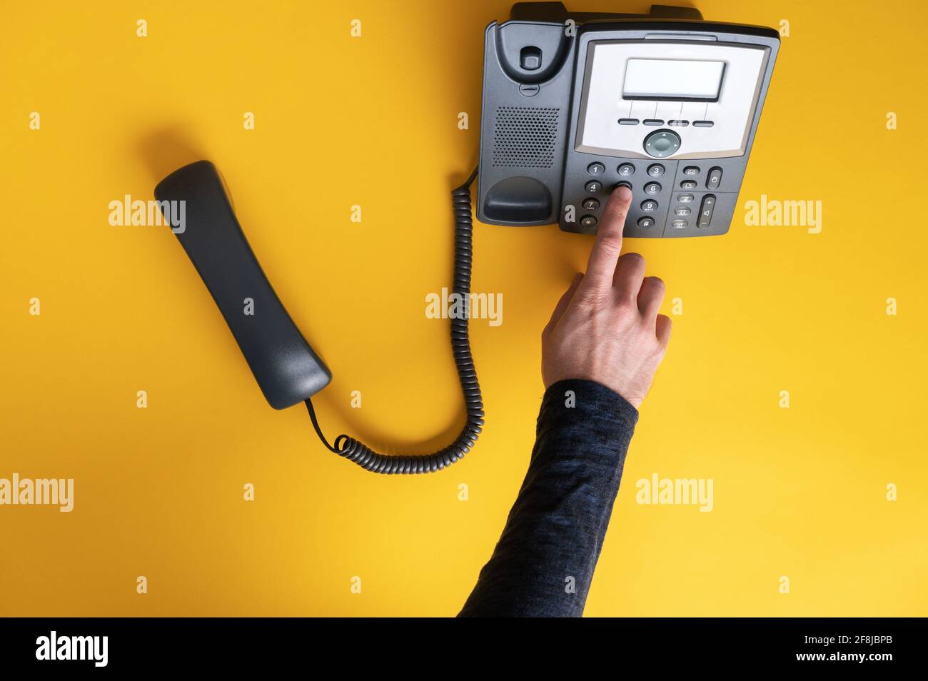 Top view of a male finger dialing a telephone number using black