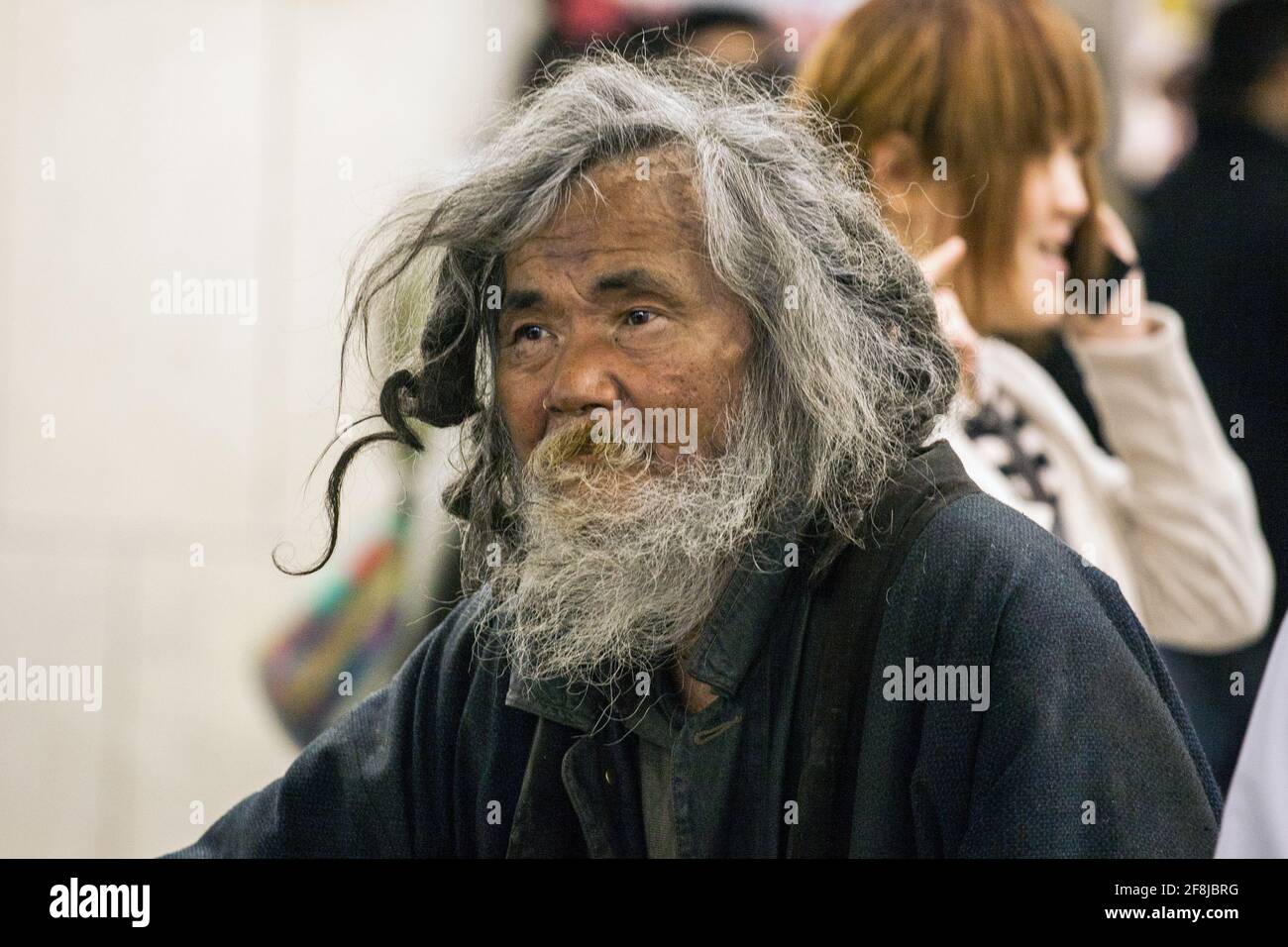 Close up portrait of disheveled, bearded homeless Japanese male, Shinjuku station, Tokyo, Japan Stock Photo