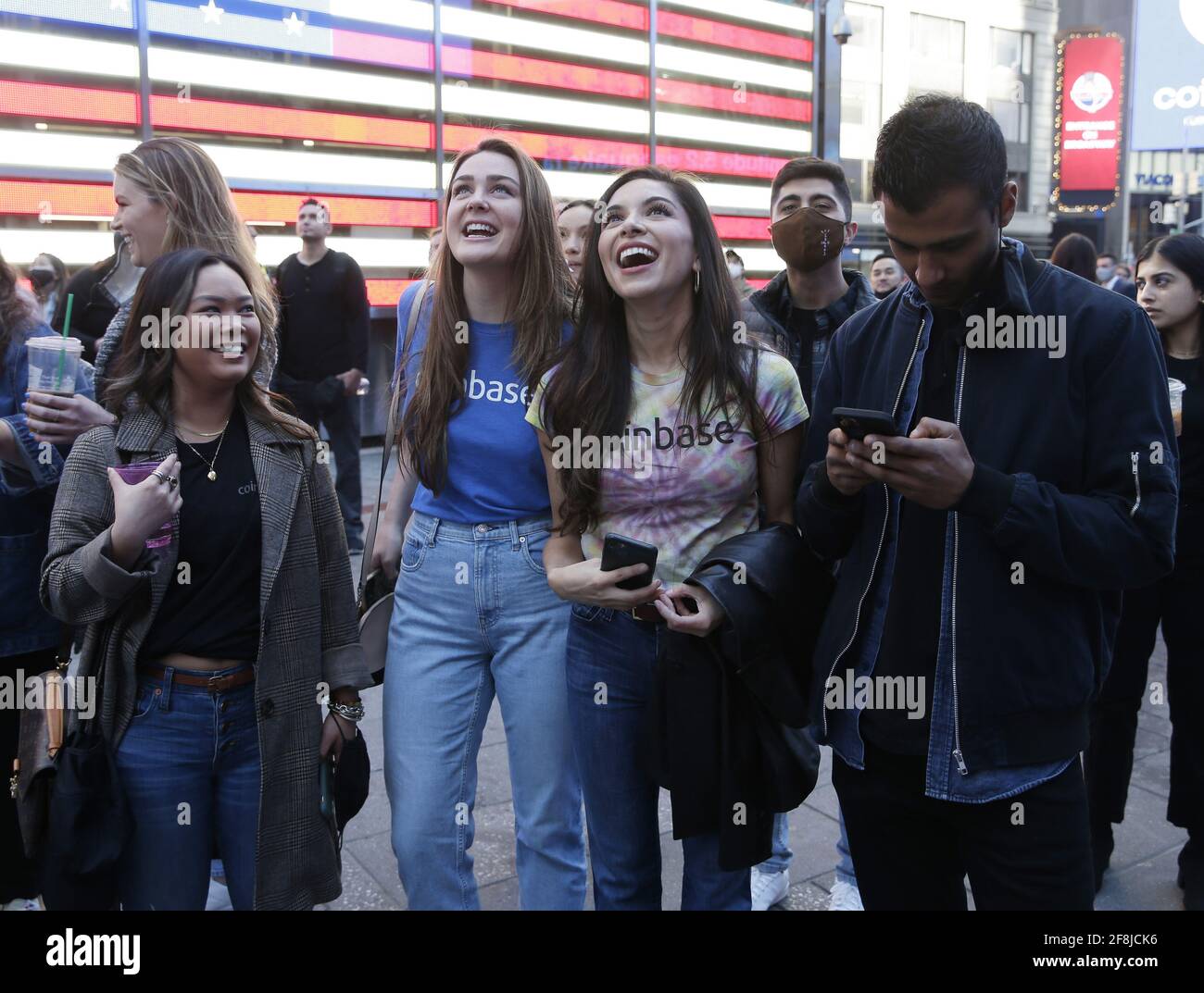 New York, United States. 14th Apr, 2021. Employees and supporters of  Coinbase look at the front of the display at the Nasdaq MarketSite where  the Coinbase logo is displayed on screens in