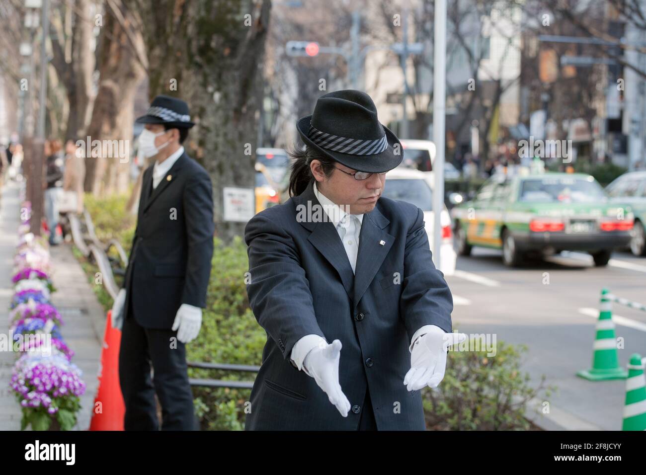 Japanese car parking attendant dressed in trilby hat guides a parker, Aoyama, Tokyo, Japan Stock Photo